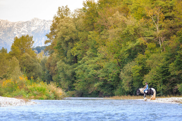 Female horse rider crossing river in a beautiful landscape