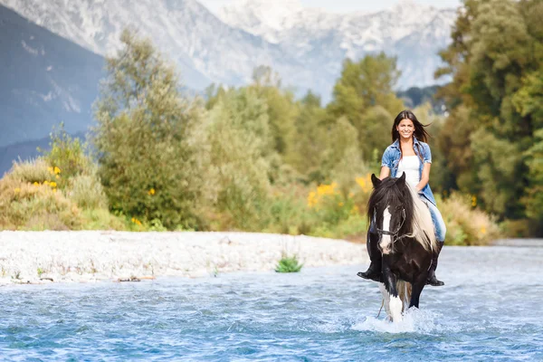 Bela fêmea cavalo cavaleiro cruzando rio no um montanhoso lan — Fotografia de Stock
