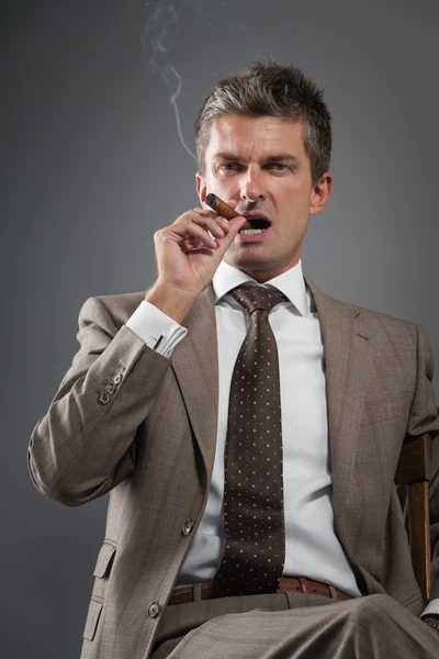 Бизнесмен курит сигару — стоковое фото