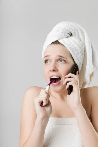 Sorprendida jovencita hablando por teléfono mientras se cepilla la camiseta — Foto de Stock