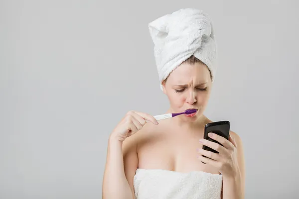 Jovem menina assistindo seu telefone incerto enquanto escovando seu tee — Fotografia de Stock