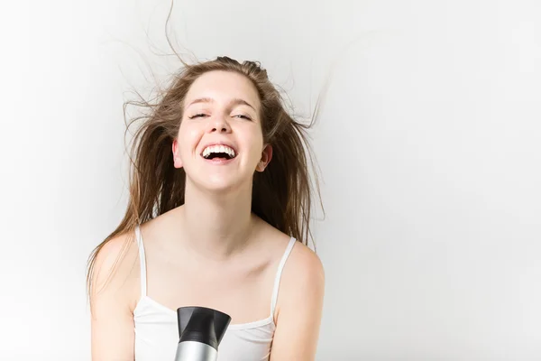 Красивая улыбчивая молодая девушка дуть сушить волосы — стоковое фото