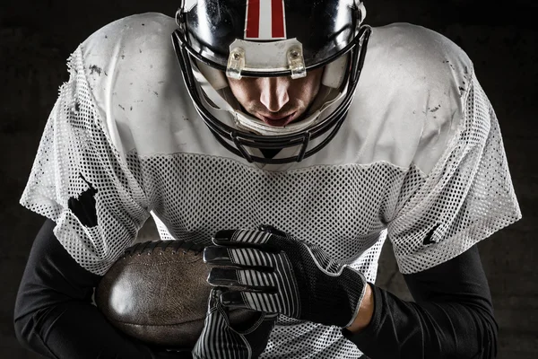 Portrait of american football player holding a ball and looking — Stock Photo, Image