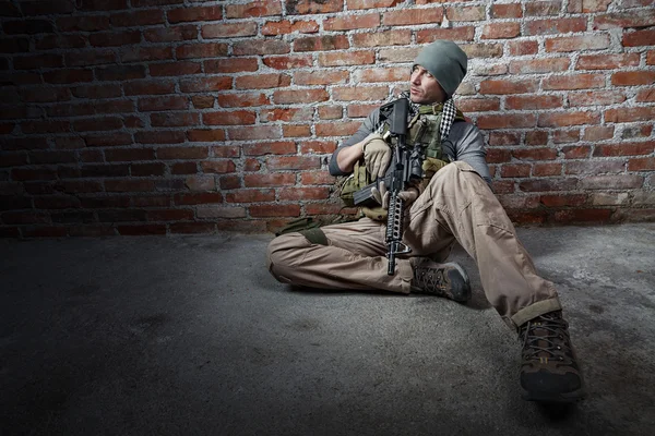 Soldat mit Gewehr auf Backsteinen Hintergrund — Stockfoto