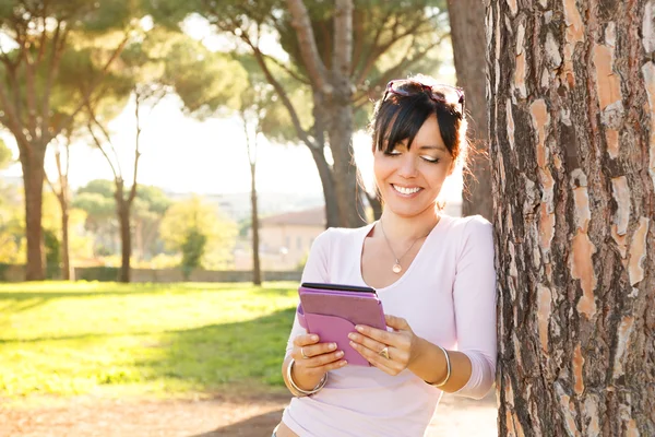 Glimlach brunette vrouw haar buiten ebook lezen — Stockfoto