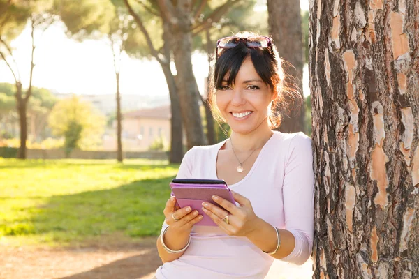 Glimlach brunette vrouw haar buiten ebook lezen — Stockfoto