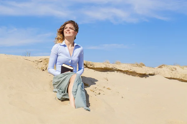 Sorridente giovane donna bionda con un libro sulla spiaggia — Foto Stock