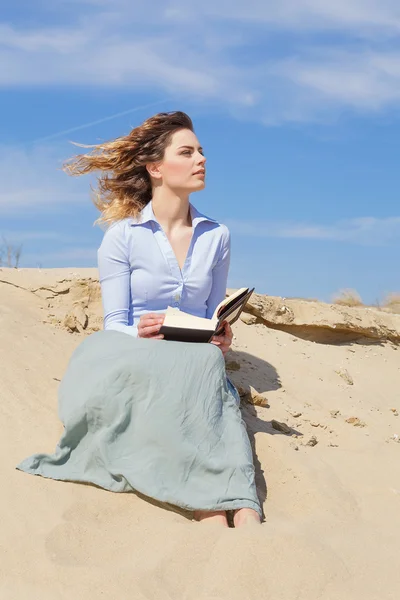 Hermosa mujer pelo viento leyendo un libro en la playa — Foto de Stock