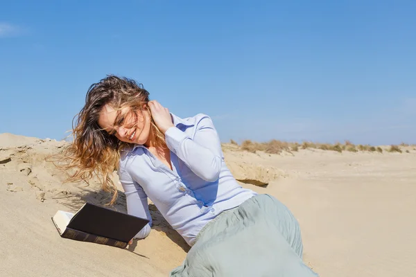 Привлекательная молодая девушка читает книгу на пляже — стоковое фото