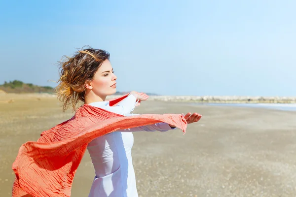 Schöne junge Frau mit rotem Schal am Strand — Stockfoto