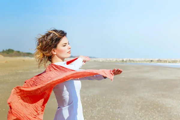 Mulher bonita com cachecol vermelho na praia — Fotografia de Stock