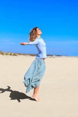 genç gülümseyen kız plajda havada yukarı atlıyor