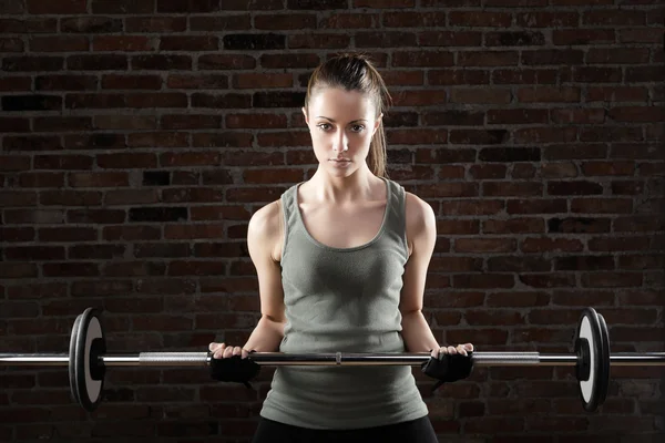 Sexy fit woman lifting dumbbells on brick background — Stock Photo, Image