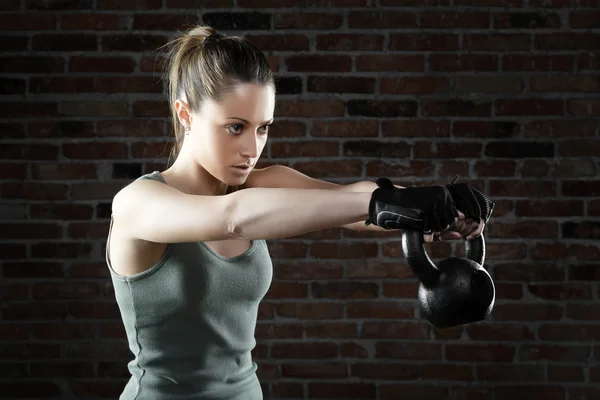 Young fit woman lifting kettle bell — Stock Photo, Image