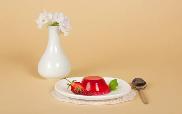 Placa con gelatina de fresa, cuchara, servilleta y jarrón con las flores —  Fotos de Stock