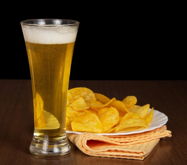 Mug à la bière, un plat avec des chips et une serviette sur une table — Photo