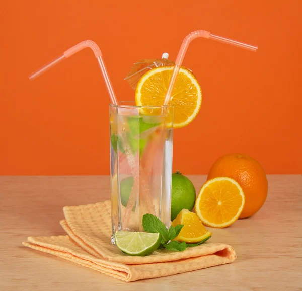 The drink glass with a straw, is decorated with an umbrella and an orange segment, a citrus and a napkin on a table — Stock Photo, Image