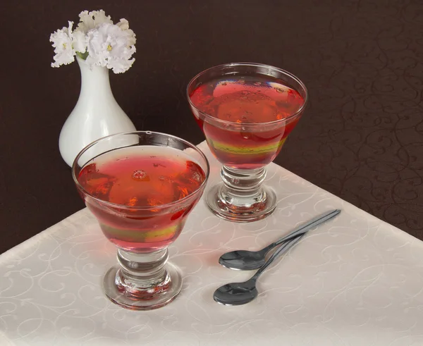 Dos vasos con la gelatina, dos cucharaditas y un jarrón con las flores en una servilleta —  Fotos de Stock