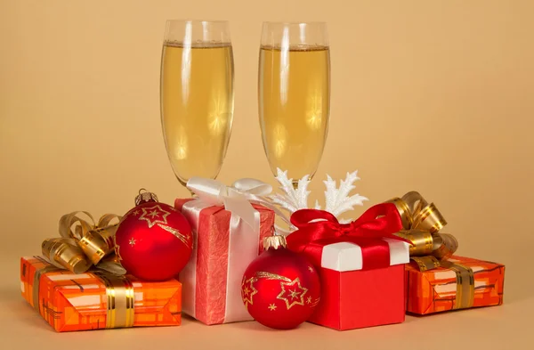 Set di scatole regalo diverse, giocattoli, un fiocco di neve e bicchieri di vino con champagne su sfondo beige — Foto Stock