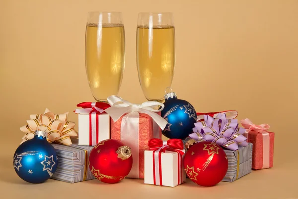 Set di scatole regalo, giocattoli e bicchieri di vino con champagne su sfondo beige — Foto Stock