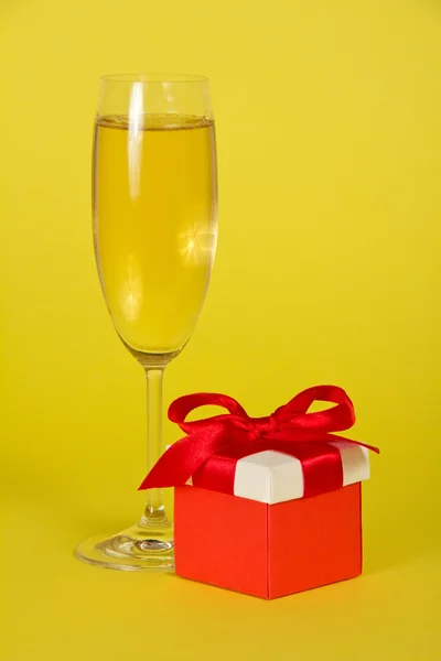 Champanhe festivo e caixa de presente brilhante em um fundo amarelo — Fotografia de Stock