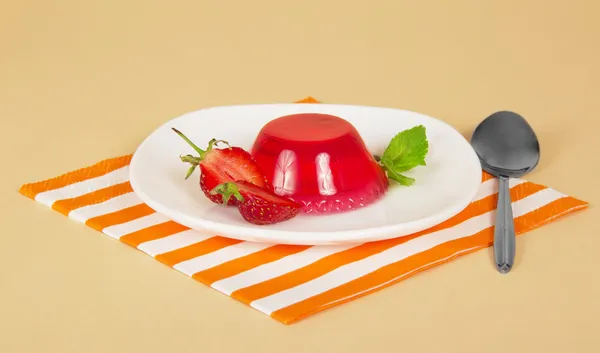Assiette avec gelée de fraises, cuillère et une serviette rayée, sur un fond beige — Photo