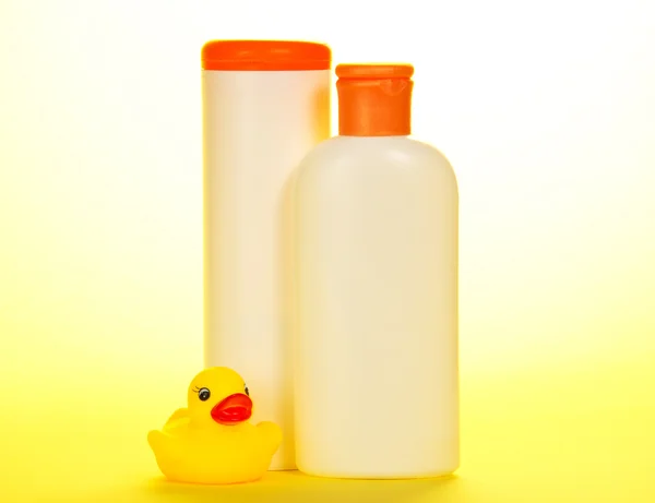 Rubber duckling and set of children's cosmetics, on a yellow background — Stock Photo, Image