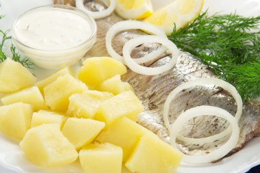 Herring and potatoes with sauce, onions a lemon and fennel, on a dish clipart