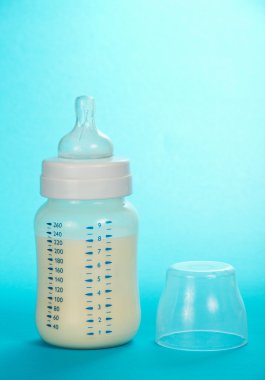 küçük şişe süt ve mavi bir arka plan üzerinde bir kapak