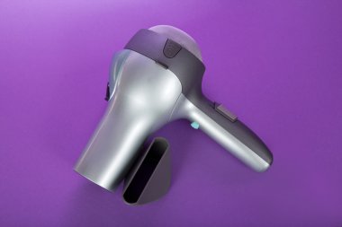 The hair dryer for drying of hair and additional accessories, on the violet clipart