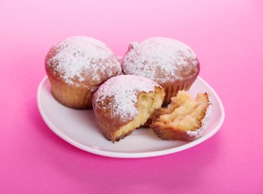 bir tabak üzerine krema şeker, pembe bir arka plan ile strewed cupcake