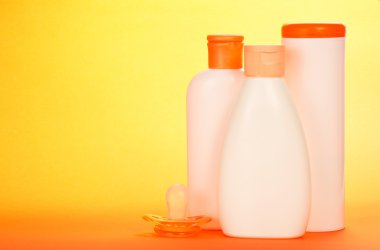 Bebek ve turuncu bir arka plan üzerinde emzik için kozmetik