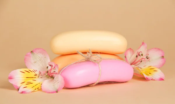 Set of toilet soap and the flower of an alstroemeria on a beige background — Stock Photo, Image