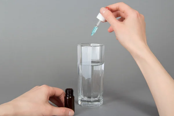 Gotas en las manos y un vaso con agua sobre un fondo gris —  Fotos de Stock