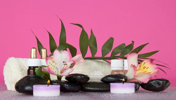 Candle, flower, stones with water decrease, before a howea leaf, on the pink — Stock Photo, Image