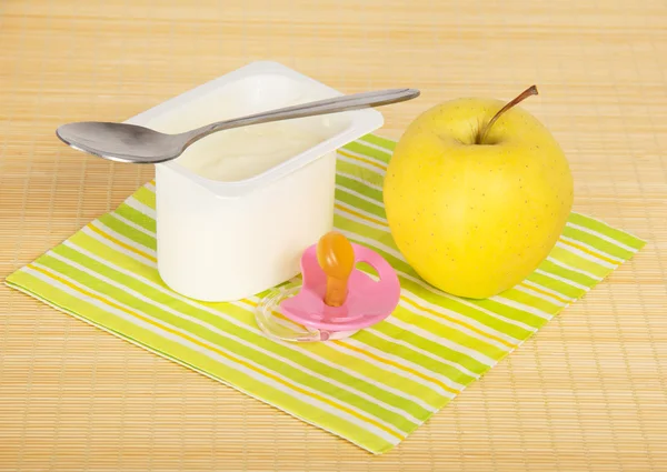 Йогурт, яблоко, соска и салфетка на бамбуковой ткани . — стоковое фото