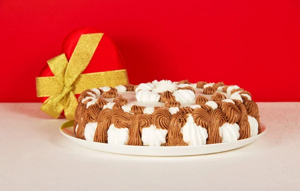 Bisküvi, bir hediye kalp üzerinde kırmızı zemin üzerinde beyaz bir bez ile çanak — Stok fotoğraf