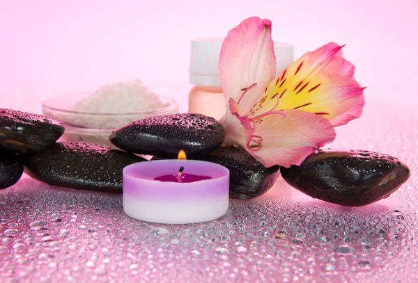 El juego de los aceites perfumados, la sal, las velas, las piedras, el hilo dental, en las gotas de agua, sobre el fondo rosado —  Fotos de Stock