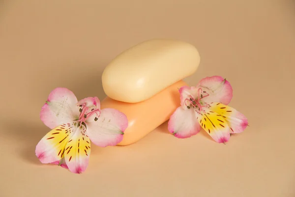 Beautiful flower of an alstroemeria and two pieces of the soap, on a beige background — Stock Photo, Image