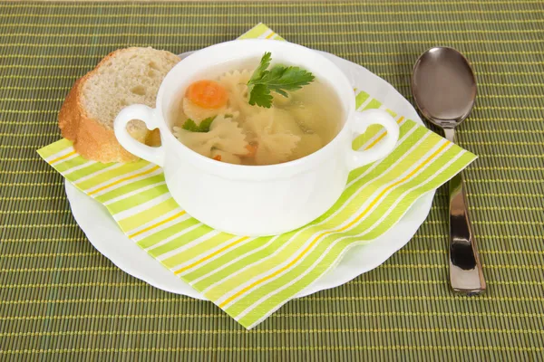 Tigela com sopa, pão, um prato, uma colher e um guardanapo em um pano de bambu verde — Fotografia de Stock