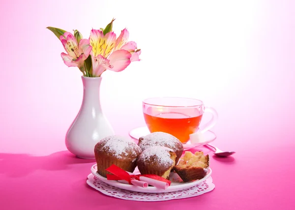 On a napkin cupcakes, tea and flowers, on the pink — Stock Photo, Image