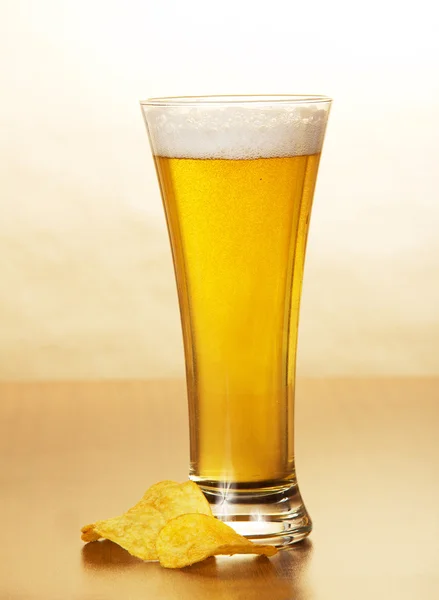 Glass of light beer and the golden chips against paper — Stock Photo, Image