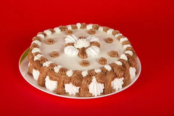 Pie on a dish, decorated with cream on a red background — Stock Photo, Image