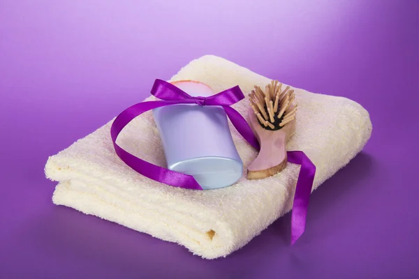 Towel, hairbrush and the shampoo, decorated with a ribbon on the violet — Stock Photo, Image