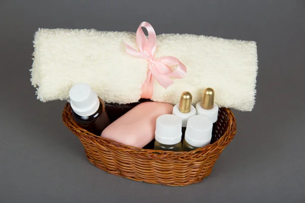 Kit de cosméticos para hotel y toalla de rizo en cesta, sobre fondo gris —  Fotos de Stock