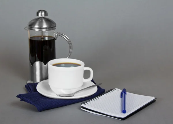 Coffee maker, cup of coffee on a napkin, a sketchpad and a ballpoint — Stock Photo, Image