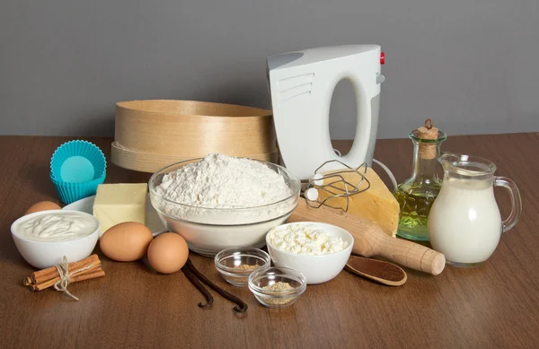 Dairy products, eggs, sunflower oil and spices, tools for dough production, on the gray — Stock Photo, Image