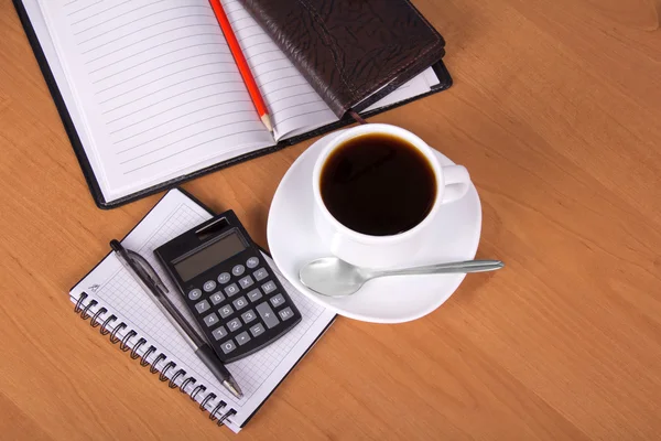 Blocco note aperto, organizzatore, fogli vuoti per note una matita, la maniglia, la calcolatrice, la tazza di caffè su un tavolo — Foto Stock
