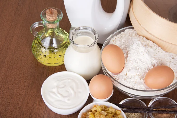 Молочные продукты, яйца, мука, подсолнечное масло, изюм, на столе — стоковое фото