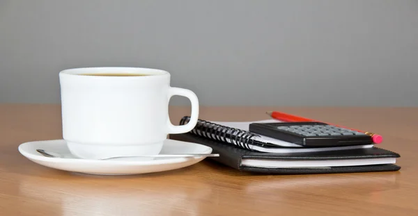 Poznámkový blok tužka kalkulačka, šálek kávy, talíř, lžíce — Stock fotografie